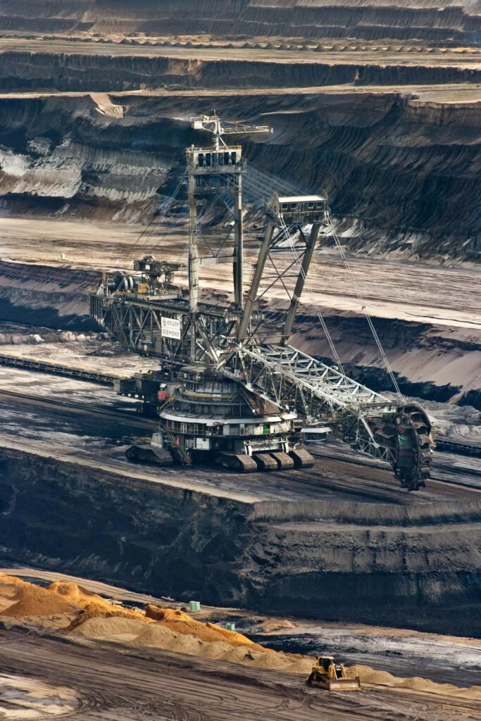 Large bucket wheel excavator operating in an open-pit mine with layered soil and coal.